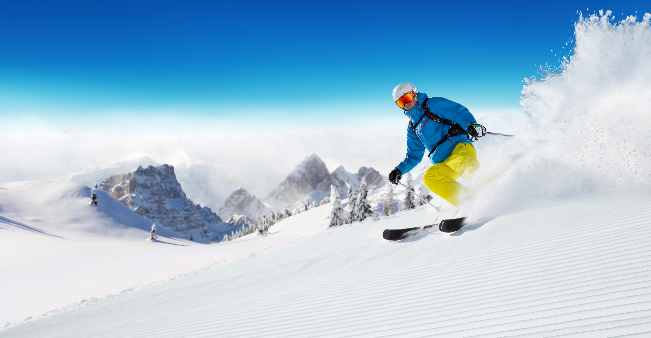 Alpinskiutøver i høy fart ned en snødekt bakke, med fokus på bevegelse og fart i et vintersportsmiljø.