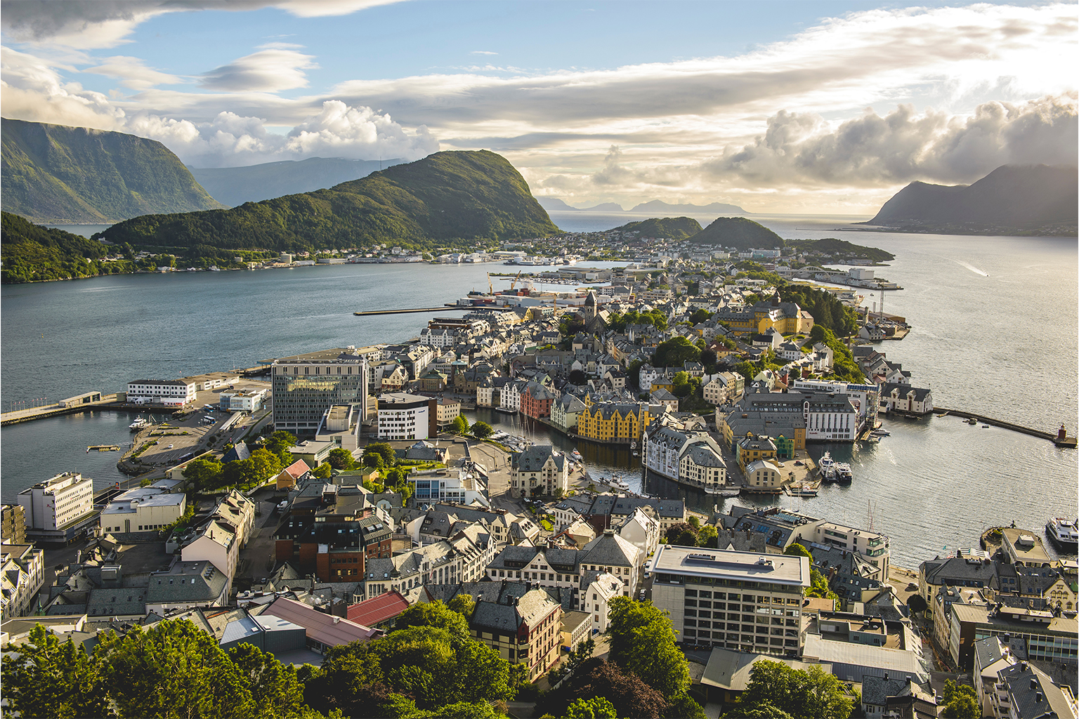 Oversiktsbilde over Ålesund by med utsikt mot sentrum, sjøen og omkringliggende øyer og fjell.