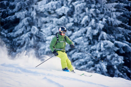 Alpinskiutøver i høy fart ned en snødekt bakke, med fokus på bevegelse og fart i et vintersportsmiljø.