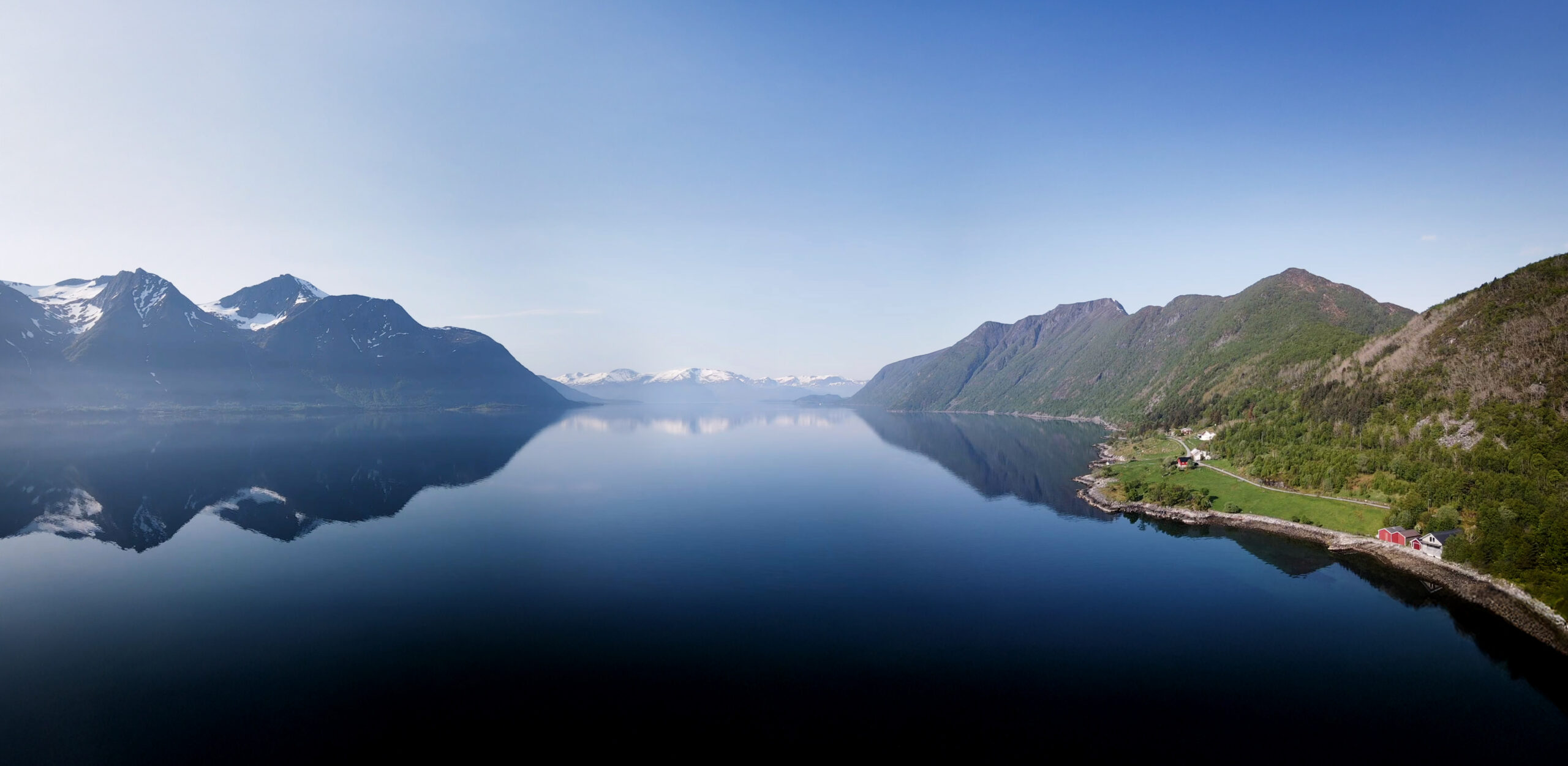 Panoramabilde over Almestranda med utsikt mot sjøen, omkringliggende fjell og deler av området rundt.